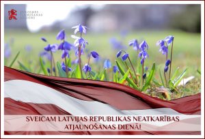 KPR apsveikums Latvijas Republikas Neatkar'bias atjaunošanas dienā, redzams sarkanbaltsarkanais karogs, kas plīvo pāri zilām Latvijas pavasara puķēm.