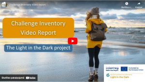 Attēlā redzams vizuālais materiāls no video prezentācijas par projektu "The Light in the Dark" ar nosaukumu "Challenge Inventory Video Report". Priekšplānā redzama sieviete dzeltenā jakā un mugursomā, kas stāv pie jūras krasta, simbolizējot dabas tuvumu un introspekciju. Fonā redzamas saulrieta gaismas un mākoņi, radot iedvesmojošu noskaņu. Attēlā iekļauti arī projekta un programmas Interreg Baltic Sea Region logotipi, norādot uz Eiropas Savienības līdzfinansējumu un reģionālo sadarbību.