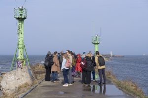 Foruma dalībnieki pulcējušies pie jūras mola Liepājā, starp navigācijas bākām, iepazīstot piekrastes infrastruktūru un jūras vidi. Vizīte sniedz ieskatu zilās ekonomikas attīstībā un piekrastes teritoriju potenciālā.