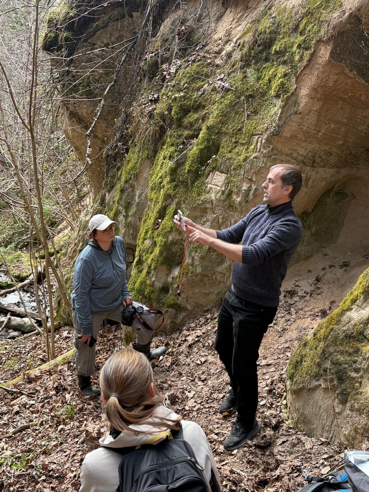 Apmācību laikā dalībnieki dabā vēro smilšakmens atsegumu Abavas ielejā, kur pasniedzējs skaidro iežu veidošanos un ģeoloģiskos procesus, izmantojot praktiskus piemērus.