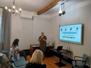 Aiga Meri seminārā Lielbornes muižā pie ekrāna stāsta dalībniekiem par Baltijas ūdenstūrisma platformu “Upesoga”.